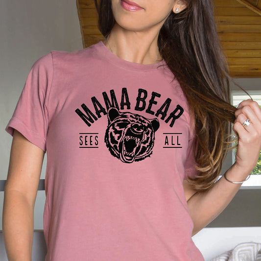 Model wearing Mama Bear Sees All peach graphic tee, casual style