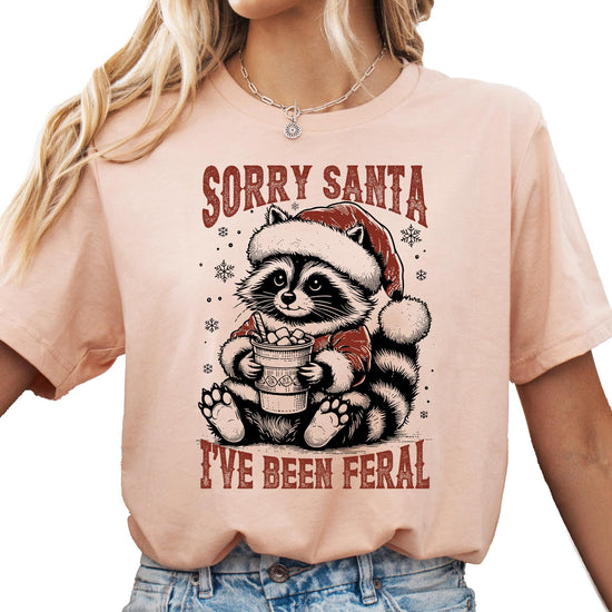 Woman wearing Sorry Santa I've Been Feral Christmas graphic tee in natural color