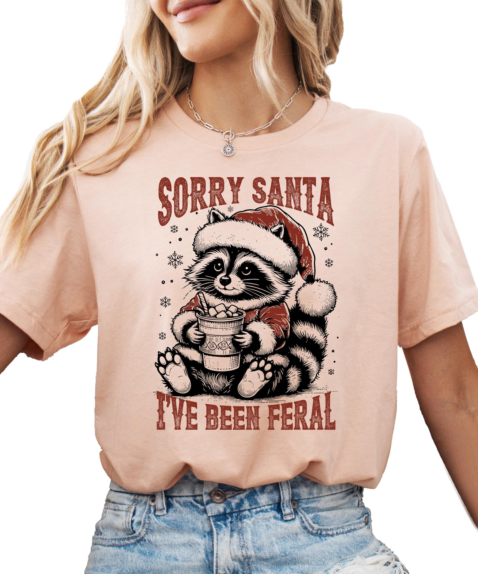 Woman wearing Sorry Santa I've Been Feral Christmas graphic tee in natural color