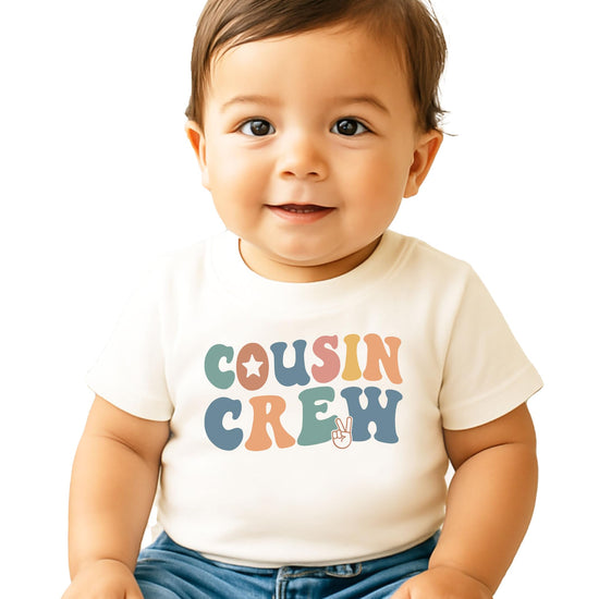 Child modeling natural colored Cousin Crew shirt with retro rainbow text