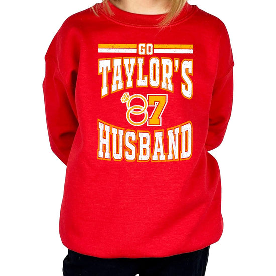 Woman wearing red Go Taylor's Husband crewneck sweatshirt styled with jeans for a casual game day look