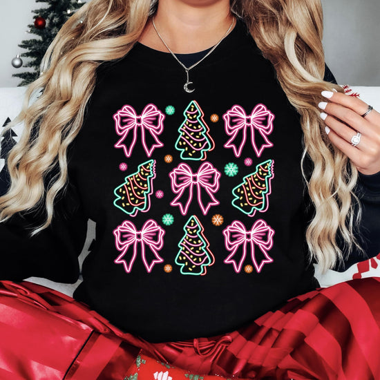 Close-up of electric neon bows and Christmas trees print on black women's holiday sweatshirt