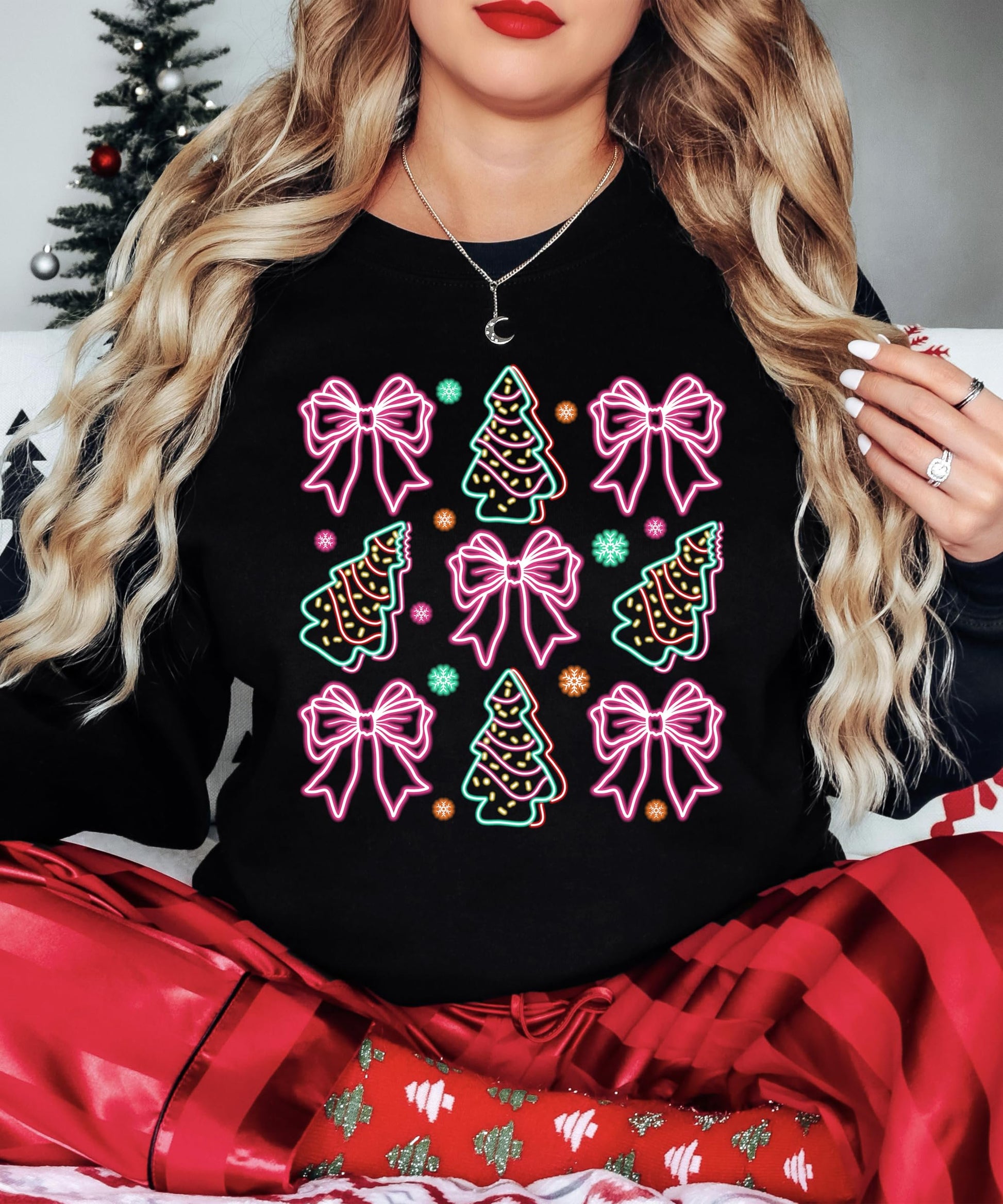 Close-up of electric neon bows and Christmas trees print on black women's holiday sweatshirt