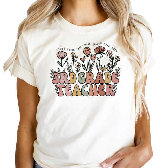 Front view of peach women's 3rd grade teacher shirt with flower garden graphic design