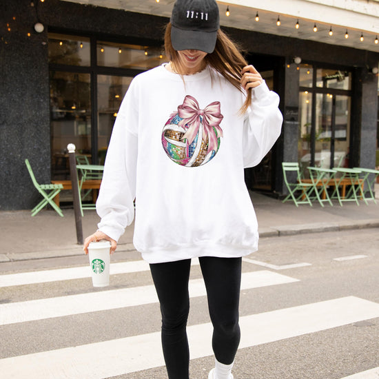 Detail shot of vibrant disco volleyball and pink bow print on gray women's sweatshirt