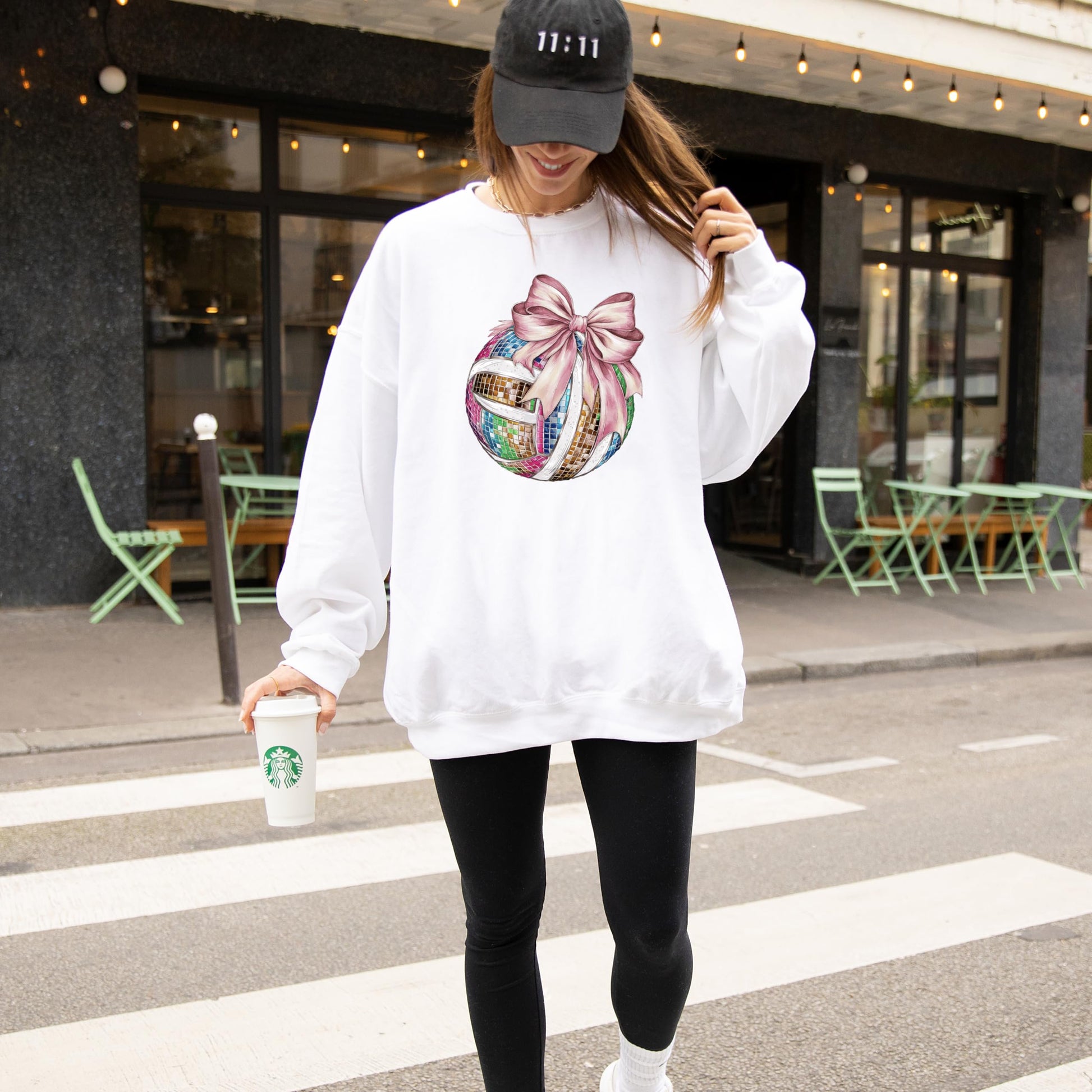 Detail shot of vibrant disco volleyball and pink bow print on gray women's sweatshirt