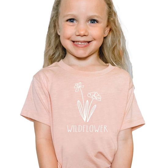 Close-up of Raising a Wildflower white graphic on mauve women's shirt