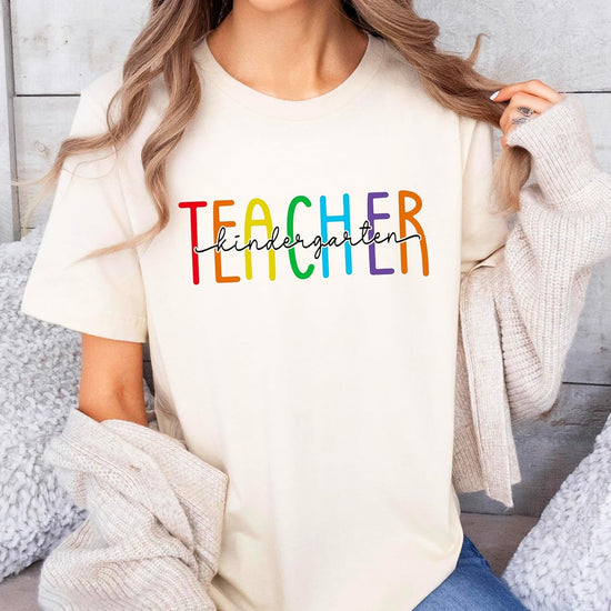 Flat lay of pink kindergarten teacher graphic tee showing full rainbow print design