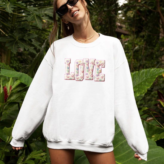 Flat lay of pink retro Valentine sweatshirt with heart graphic, styled for Valentine's Day