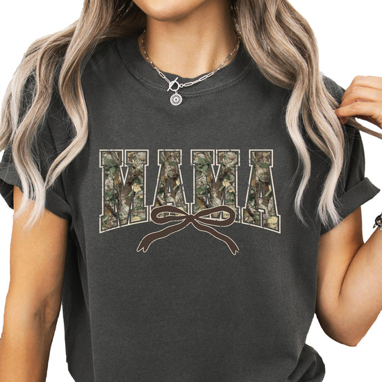 Close-up of camo varsity Mama graphic tee with pink coquette bow detail on seafoam shirt