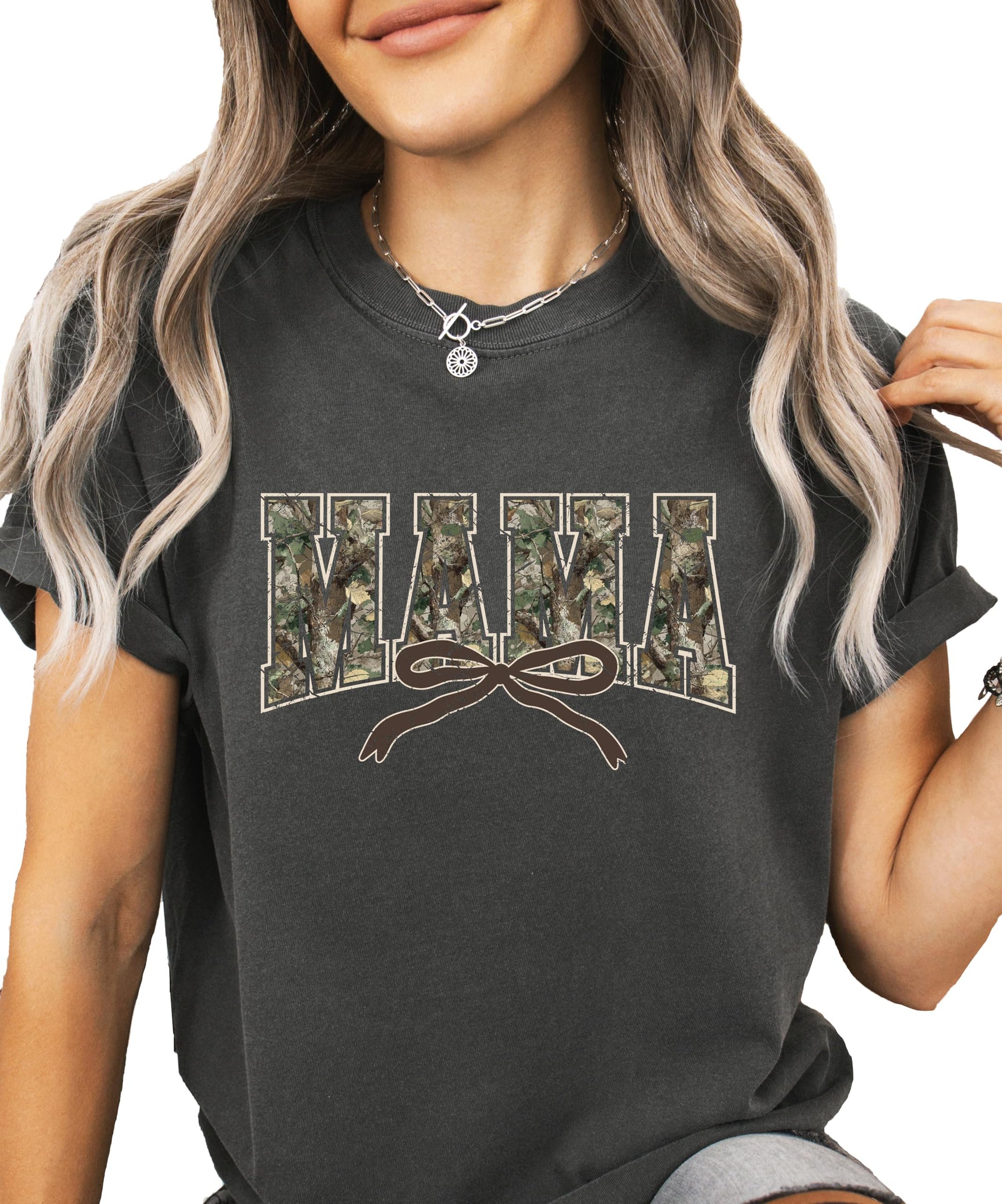 Close-up of camo varsity Mama graphic tee with pink coquette bow detail on seafoam shirt