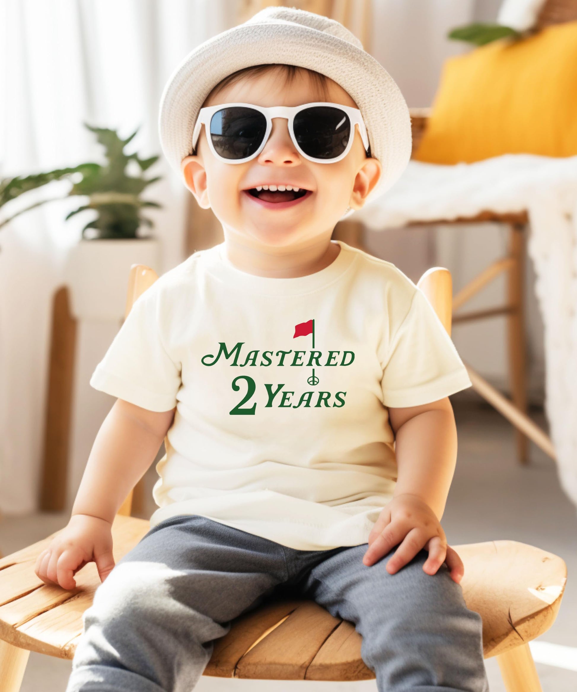 Close-up of golf birthday graphic print on natural kids tee saying Mastered 2 Years
