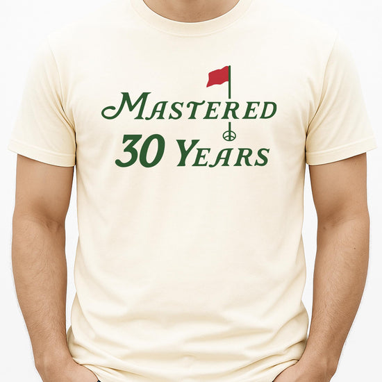 Mastered 30 Years unisex golf tee laid flat showing full shirt design and natural fabric color