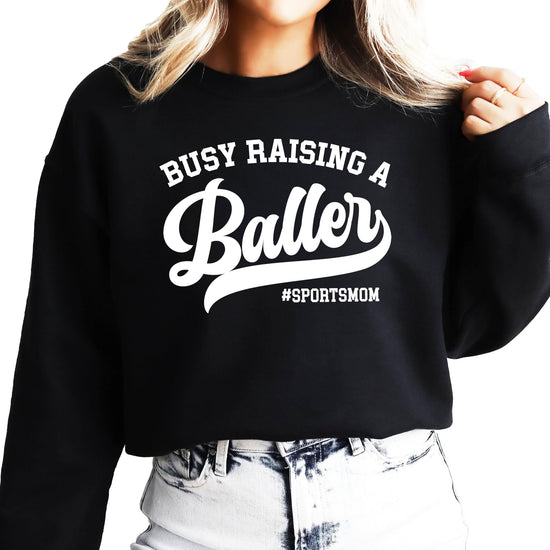 Close-up of Busy Raising a Baller graphic print detail on women's black sweatshirt