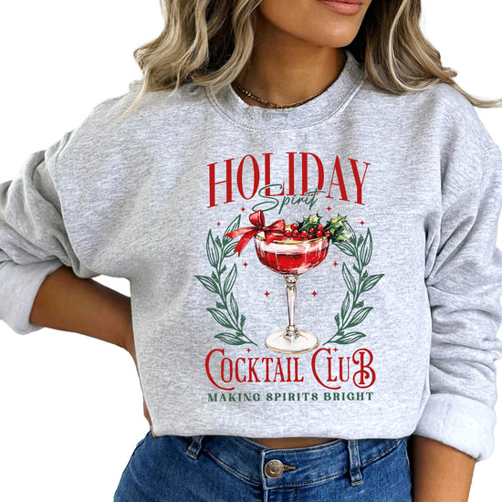 Lifestyle photo of women's funny Holiday Spirit Cocktail Club Christmas sweatshirt laid flat