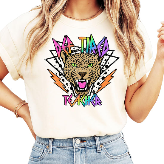Def Tired Teacher ivory graphic tee with retro tiger face and neon lightning bolt text design