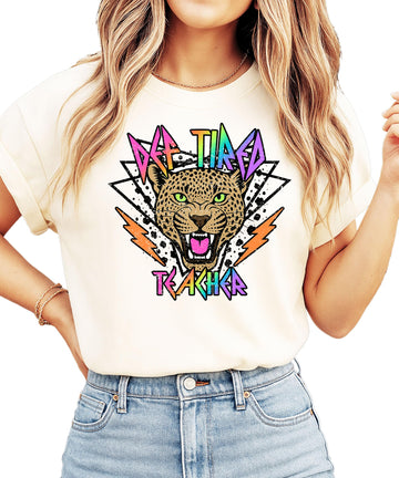 Def Tired Teacher ivory graphic tee with retro tiger face and neon lightning bolt text design