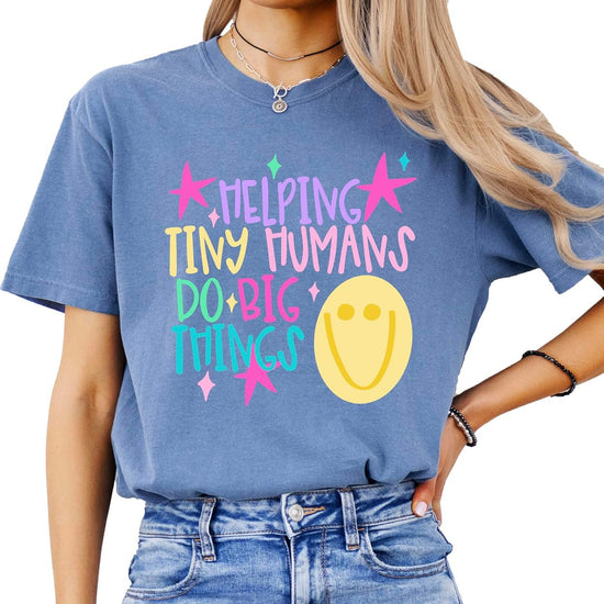Close-up of Helping Tiny Humans Do Big Things pastel hand-lettered design with stars and retro doodle on a teacher graphic tee