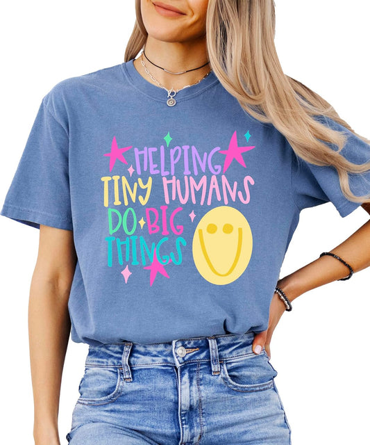 Close-up of Helping Tiny Humans Do Big Things pastel hand-lettered design with stars and retro doodle on a teacher graphic tee