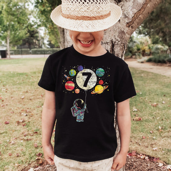 Child wearing vintage royal blue 7th birthday astronaut graphic tee with space design