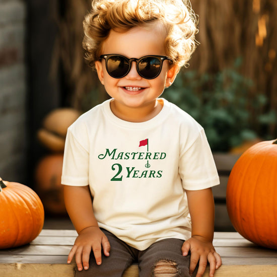 Toddler boys golf themed second birthday shirt laid flat on neutral background