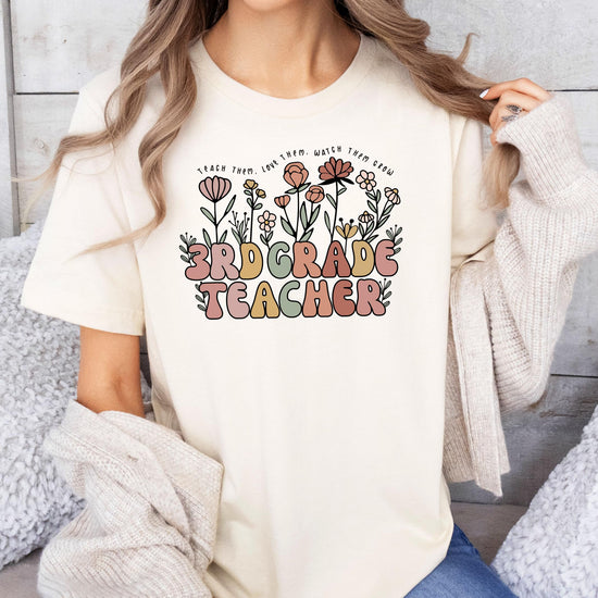 Back or alternate angle of women's peach floral teacher graphic tee from Olive Loves Apple