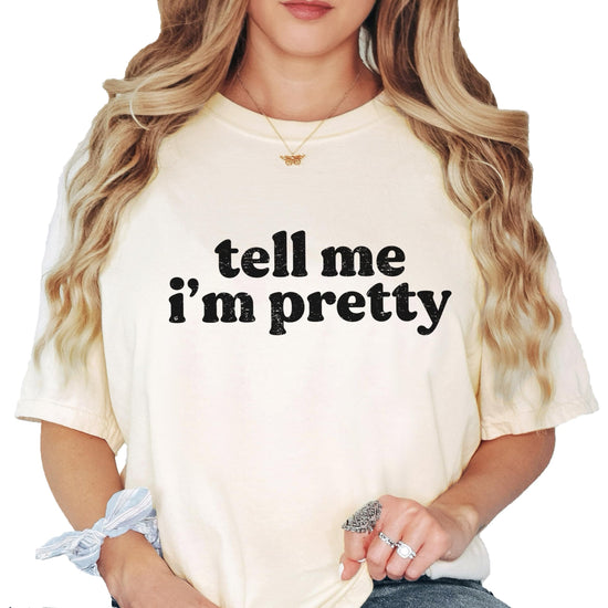 Model wearing Tell Me I'm Pretty ivory graphic tee styled casually