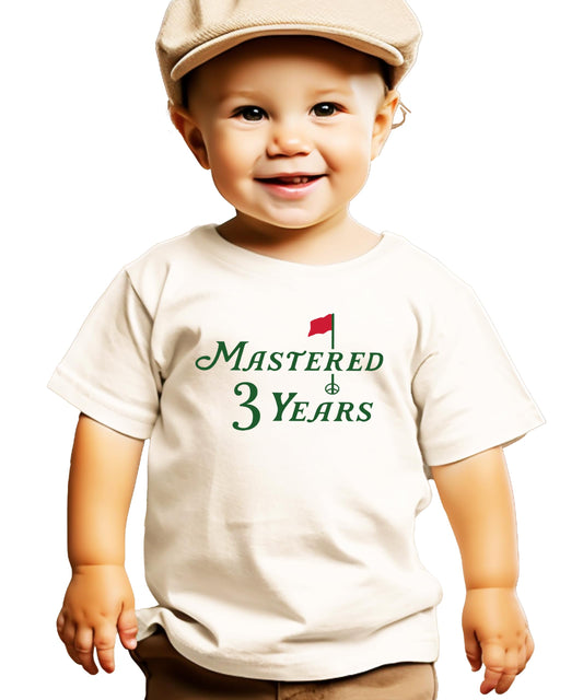 Close-up of Mastered 3 Years golf birthday graphic on a natural colored toddler shirt