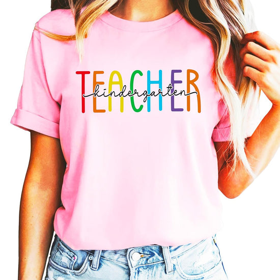 Front view of rainbow kindergarten teacher graphic tee in pink on female model