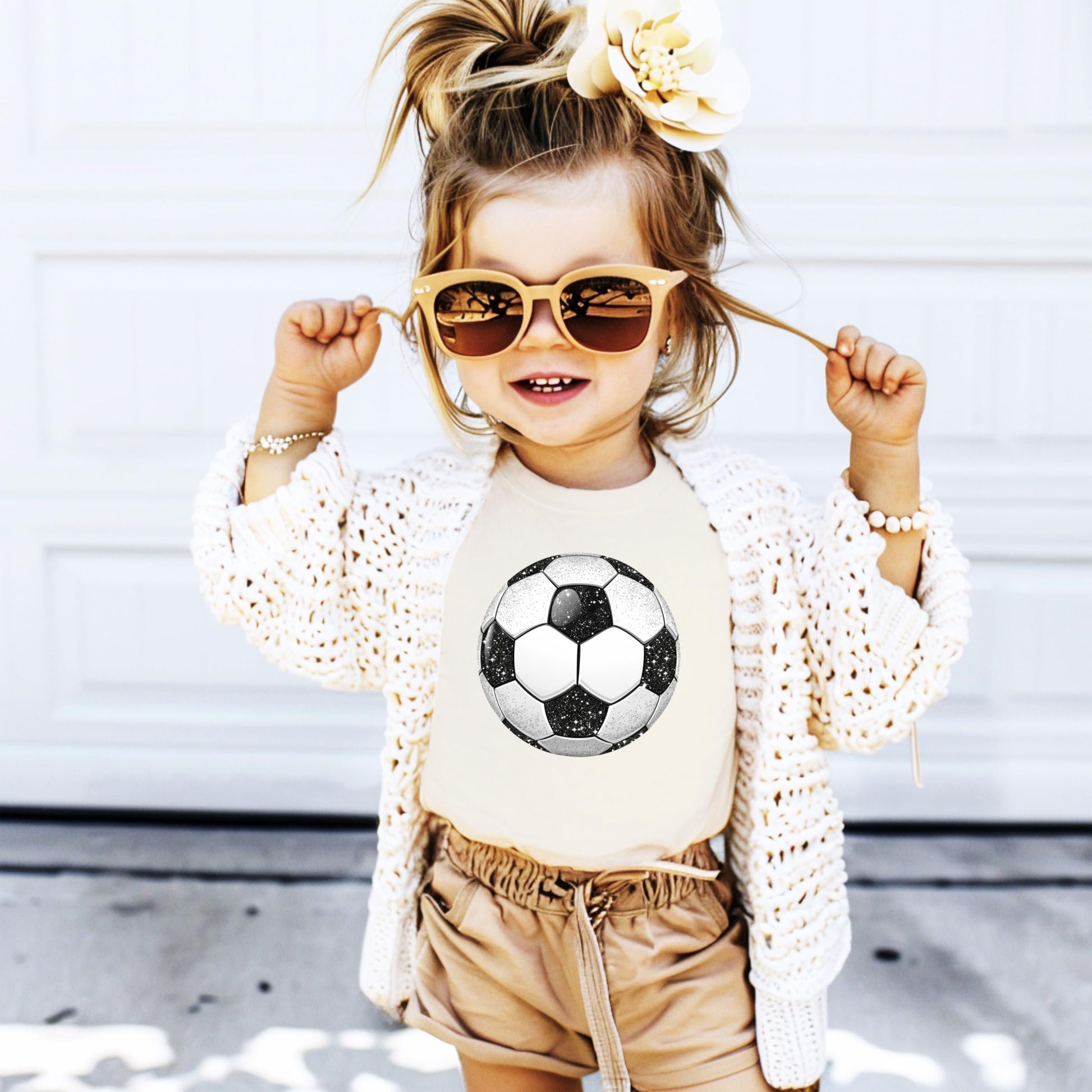 Detail shot of soft fabric and glitter soccer ball print on black children's tee