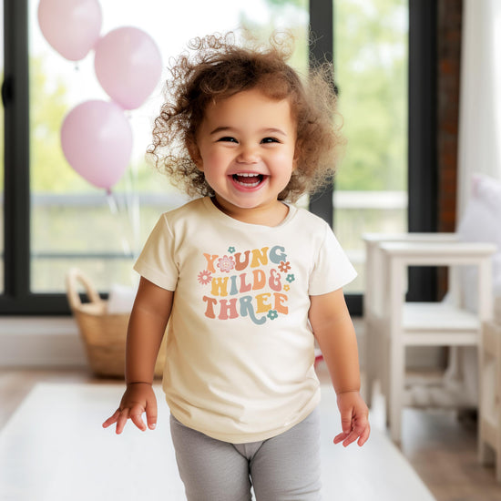 Young Wild Three daisy birthday shirt flat lay styling shot