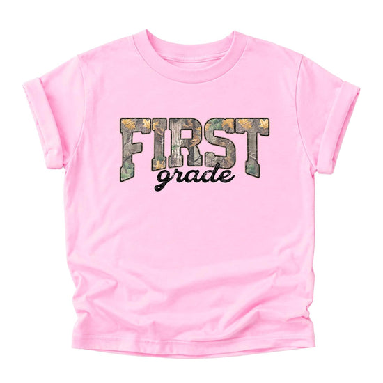 Girl wearing First Grade camo tee in pink — fun 1st grade back to school shirt for kids