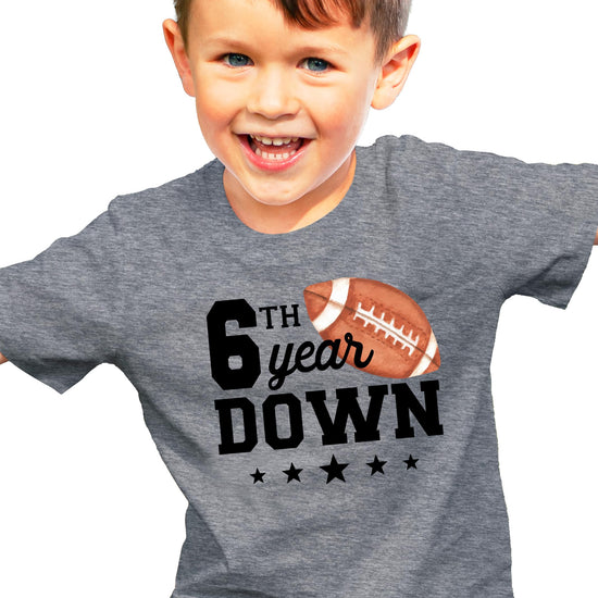Close-up of 6th Year Down football print on natural kids birthday tee
