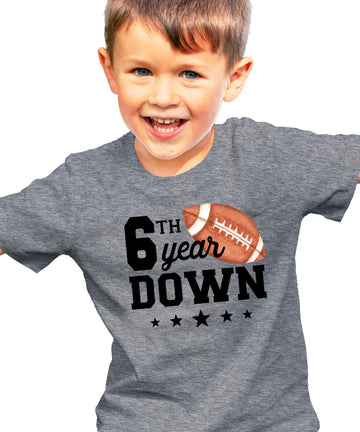 Close-up of 6th Year Down football print on natural kids birthday tee