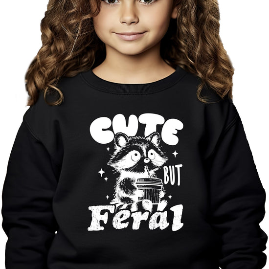 Detail shot of the raccoon graphic and Cute But Feral text on a kids pink sweatshirt