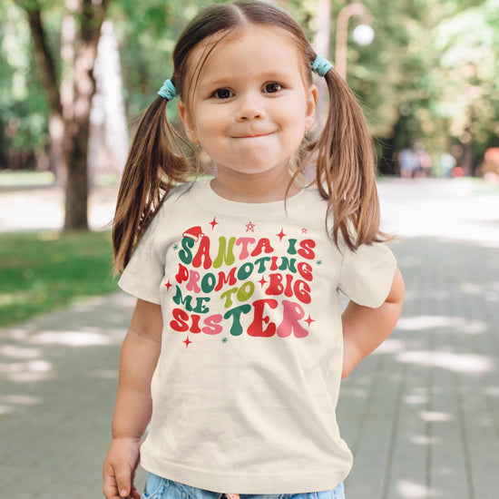 Close-up of groovy retro style lettering on big sister Christmas announcement shirt