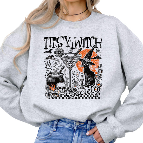 Close-up of Tipsy Witch Society graphic on black women's Halloween sweatshirt showing cauldron and cat details