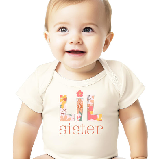 Close-up of floral graphic print on peach little sister baby one-piece bodysuit