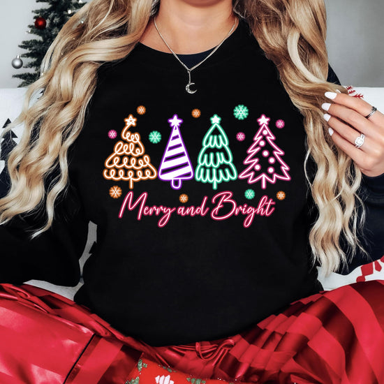 Close-up of neon Christmas tree graphic on black women's holiday sweatshirt by Olive Loves Apple