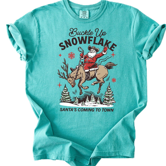 Ivory unisex western Christmas tee with cowboy Santa riding a reindeer snowflake design — front view