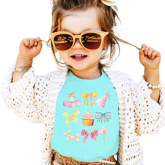 Front view of pink coquette birthday t-shirt for girls featuring pastel watercolor party icons and bow details