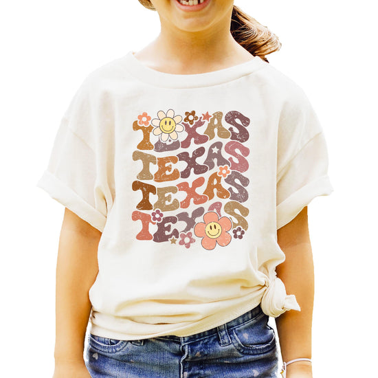 Close-up view of multicolor TEXAS text with vintage smiley face flowers on comfortable graphic tee