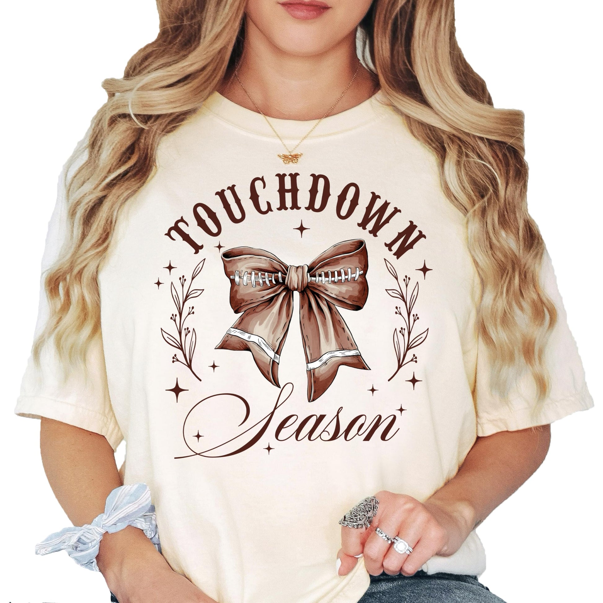 Ivory Touchdown Season football t-shirt with pink bow graphic for women and teens
