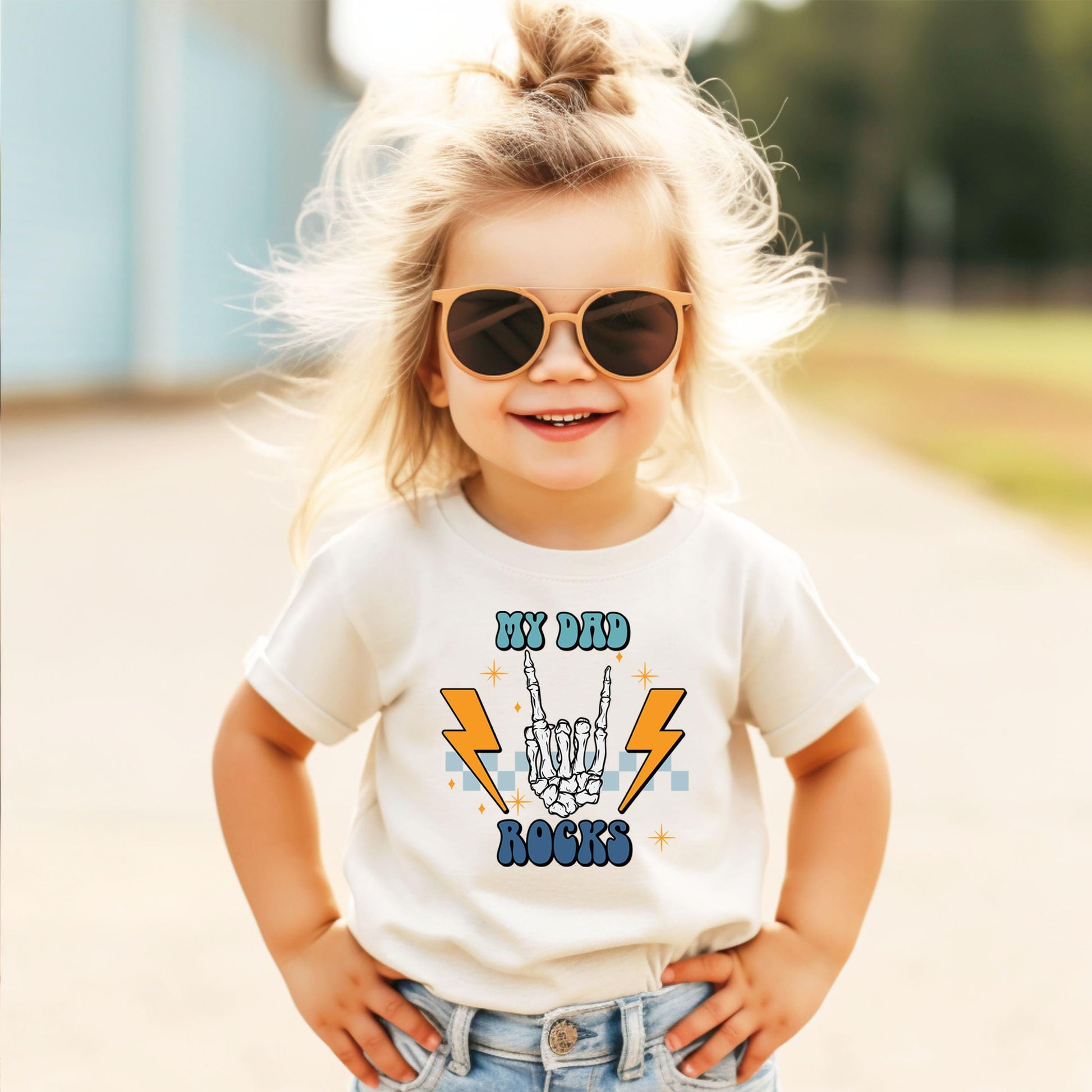 Close-up of skeleton hand rock graphic print on natural color kids tee