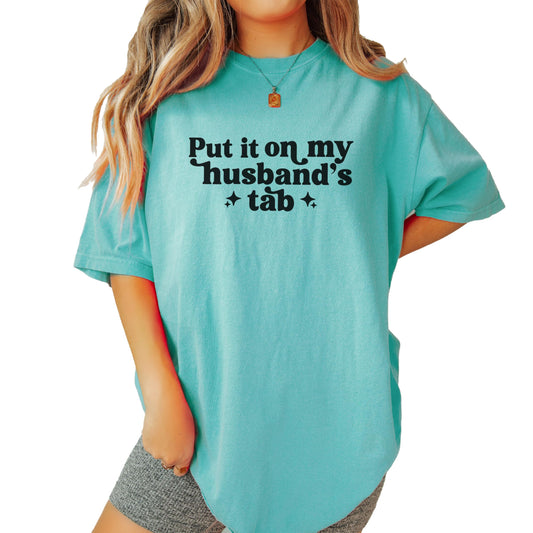 Close-up of Put it on My Husband's Tab text design on comfort colors t-shirt