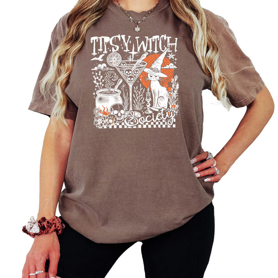 Close-up of Tipsy Witch Society shirt design showing black cat, skull, cocktail glass, and bubbling cauldron details