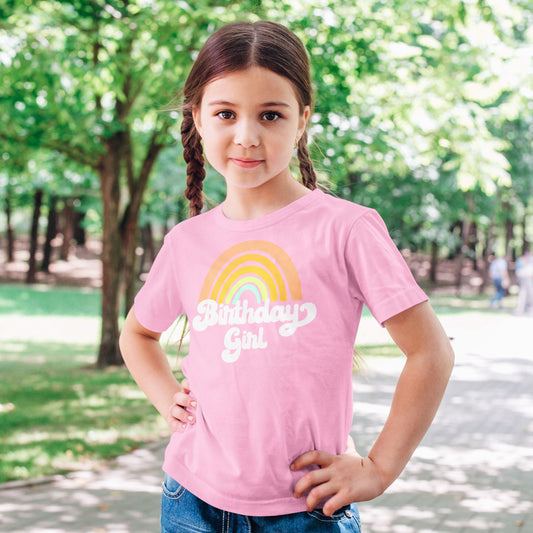 Full outfit view of toddler wearing peach rainbow birthday girl shirt