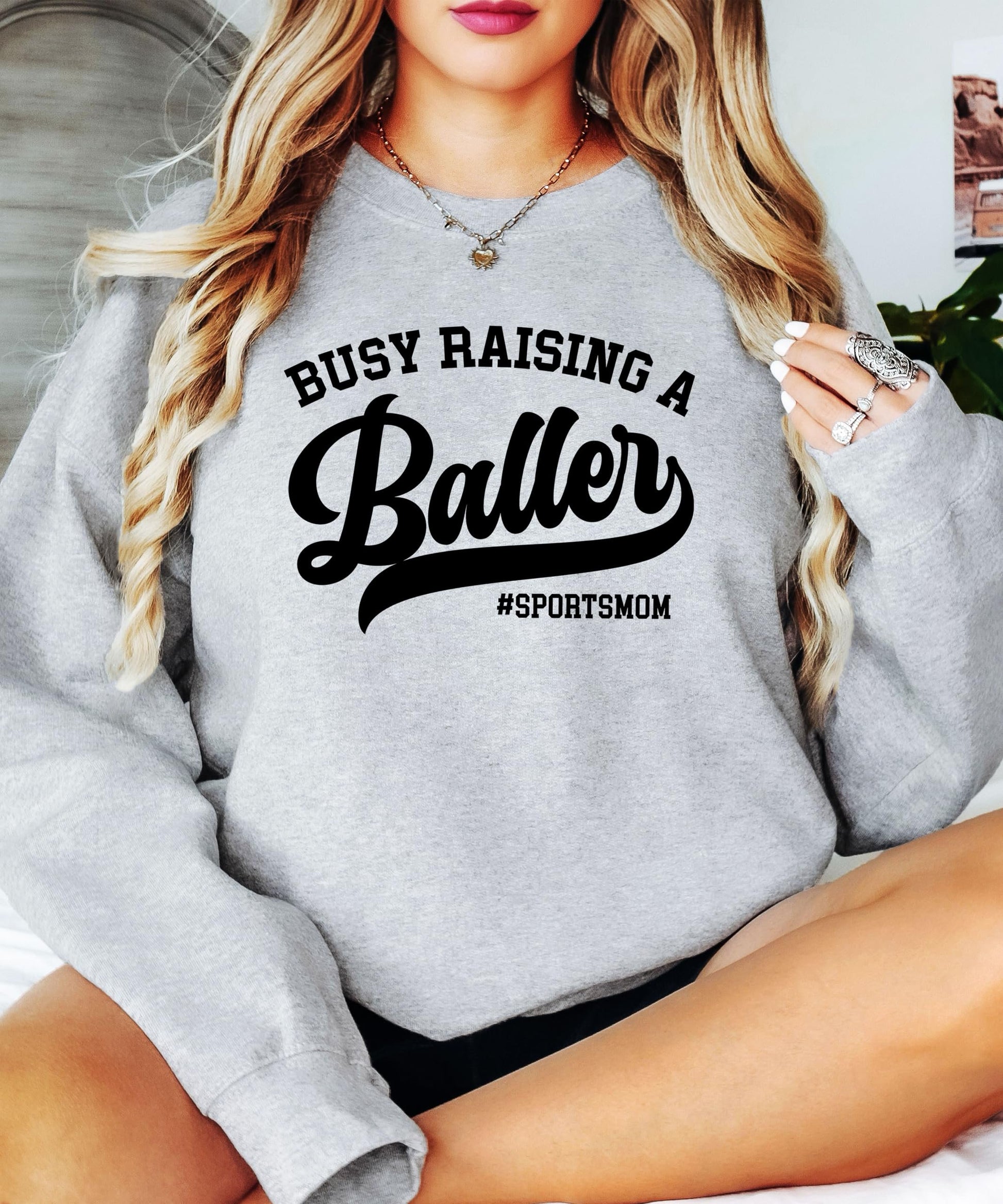 Lifestyle flat lay of women's black sports mom sweatshirt with baller graphic design