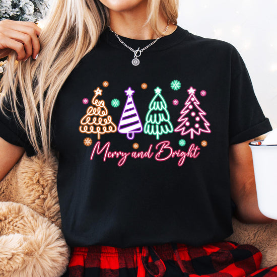 Close-up of vibrant neon Christmas tree design on black holiday graphic shirt
