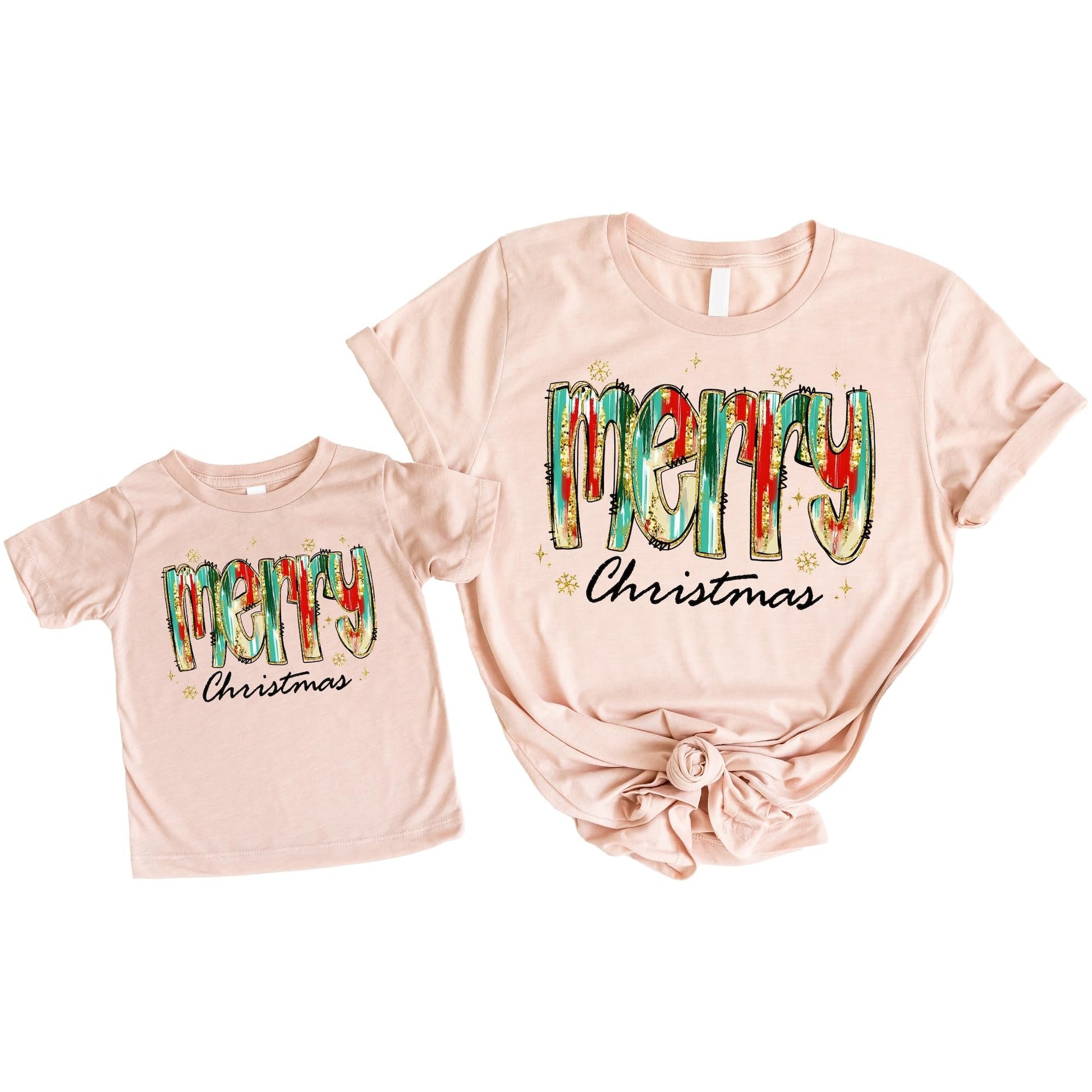 Adult and child wearing matching watercolor Christmas graphic tees in peach